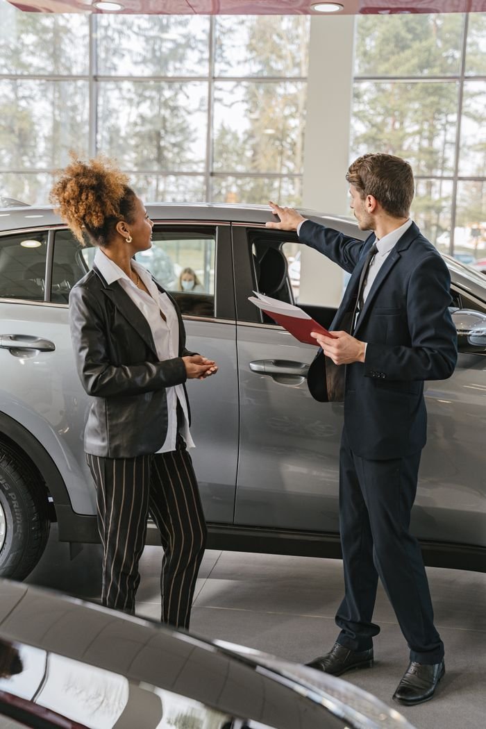 Services A woman and a car salesman discuss vehicle options inside a dealership.